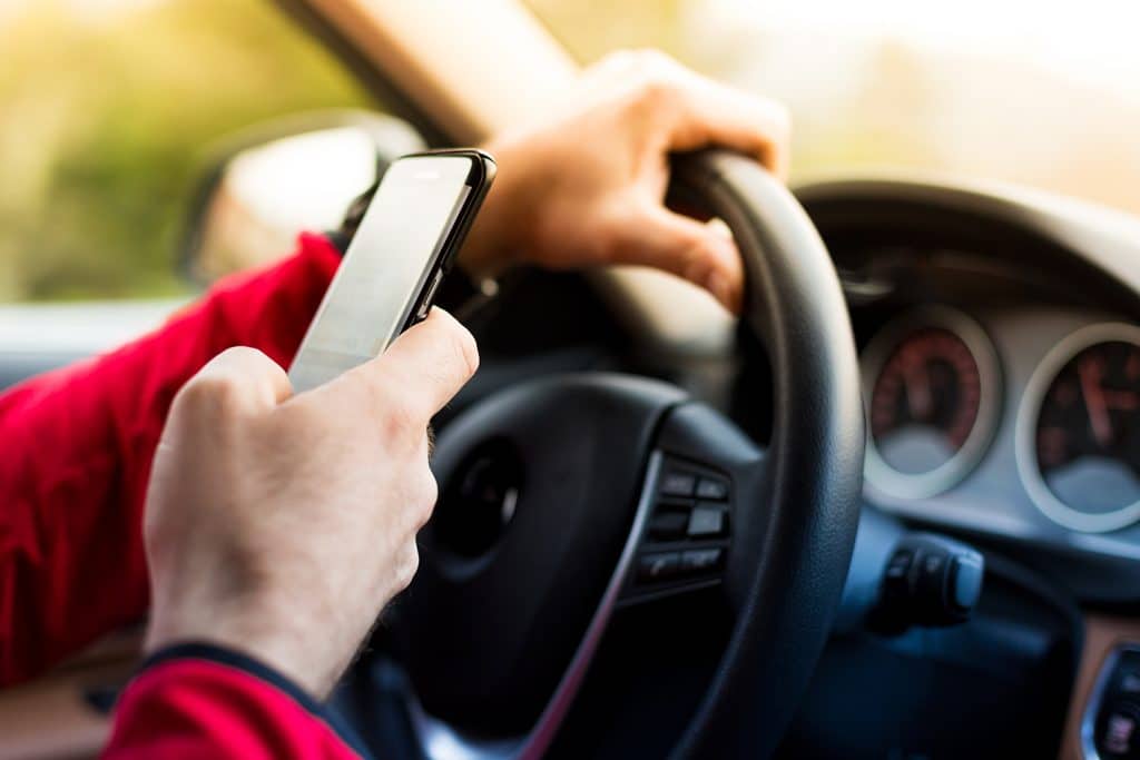 someone texting behind steering wheel