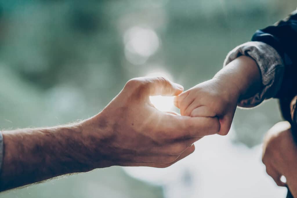 baby holding hands with adult