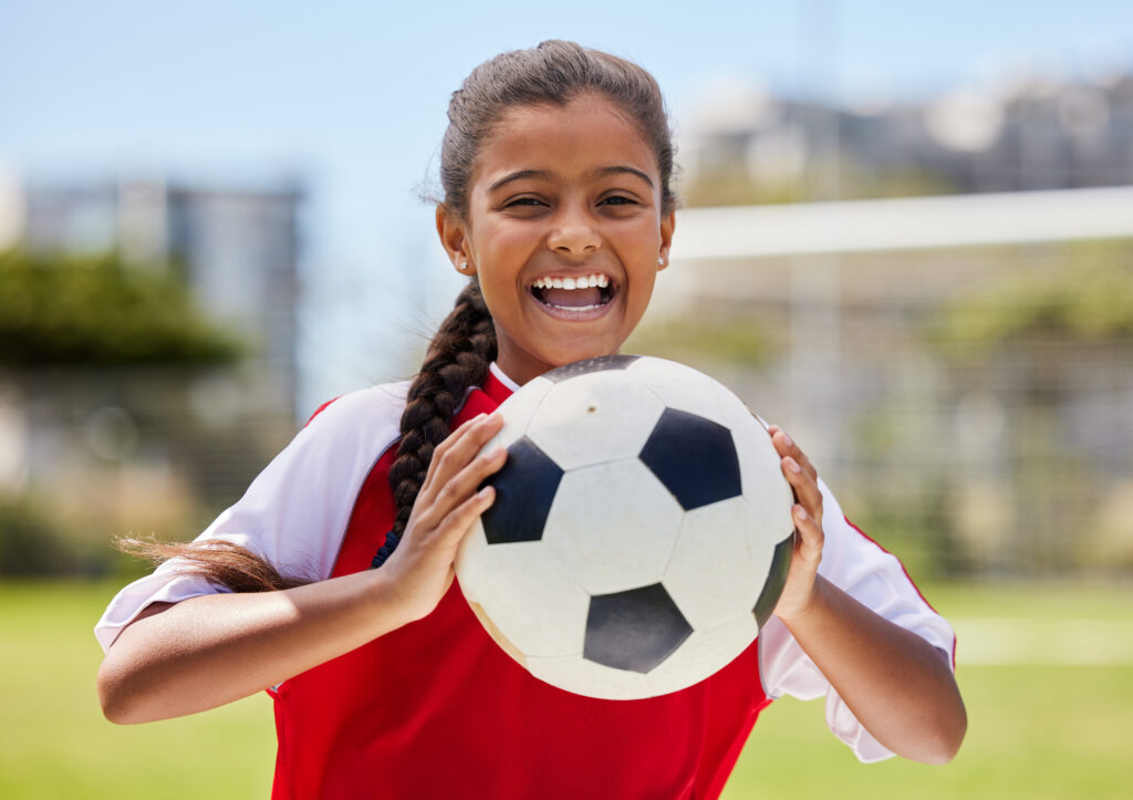 young smiling girl holding a soccer ball