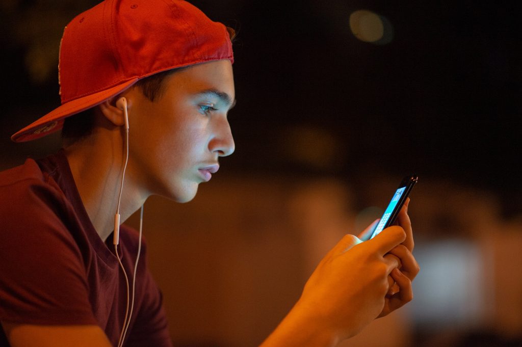 boy in red hat looking at cell phone