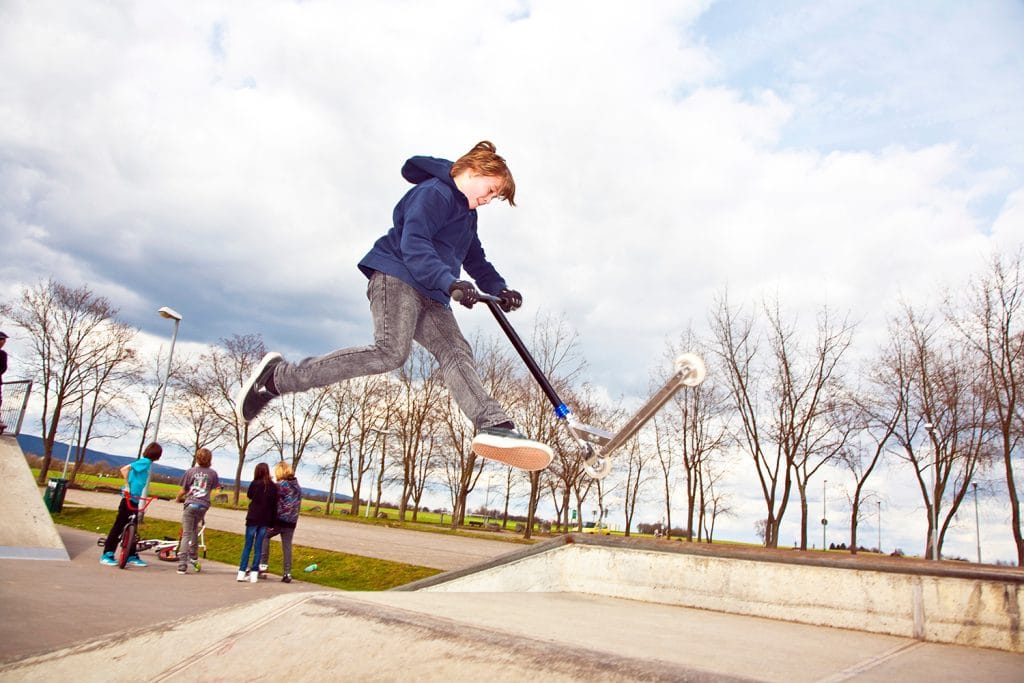 young boy doing a scooter trick in the air