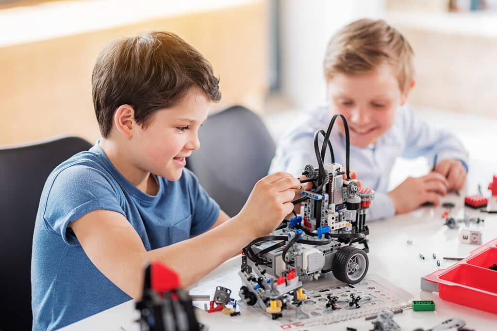 two smiling boys building a lego robot