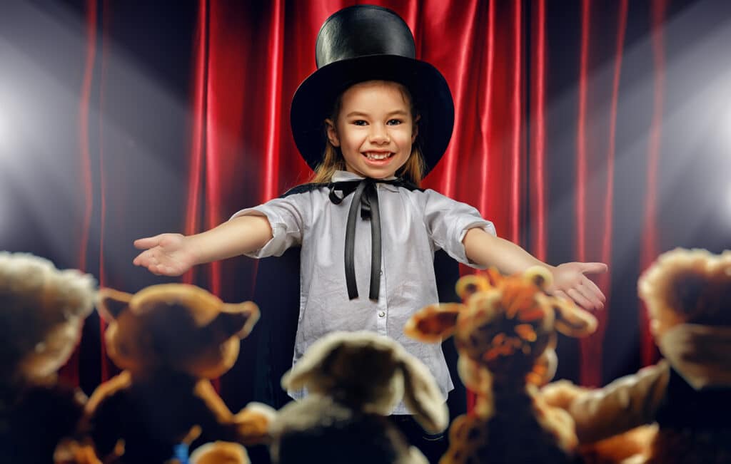 little girl performing a magic show to stuffed animals