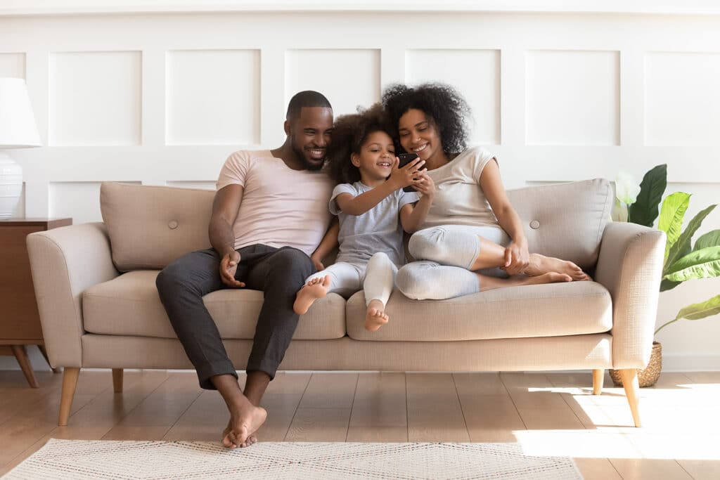 happy family sitting on a couch looking at a phone