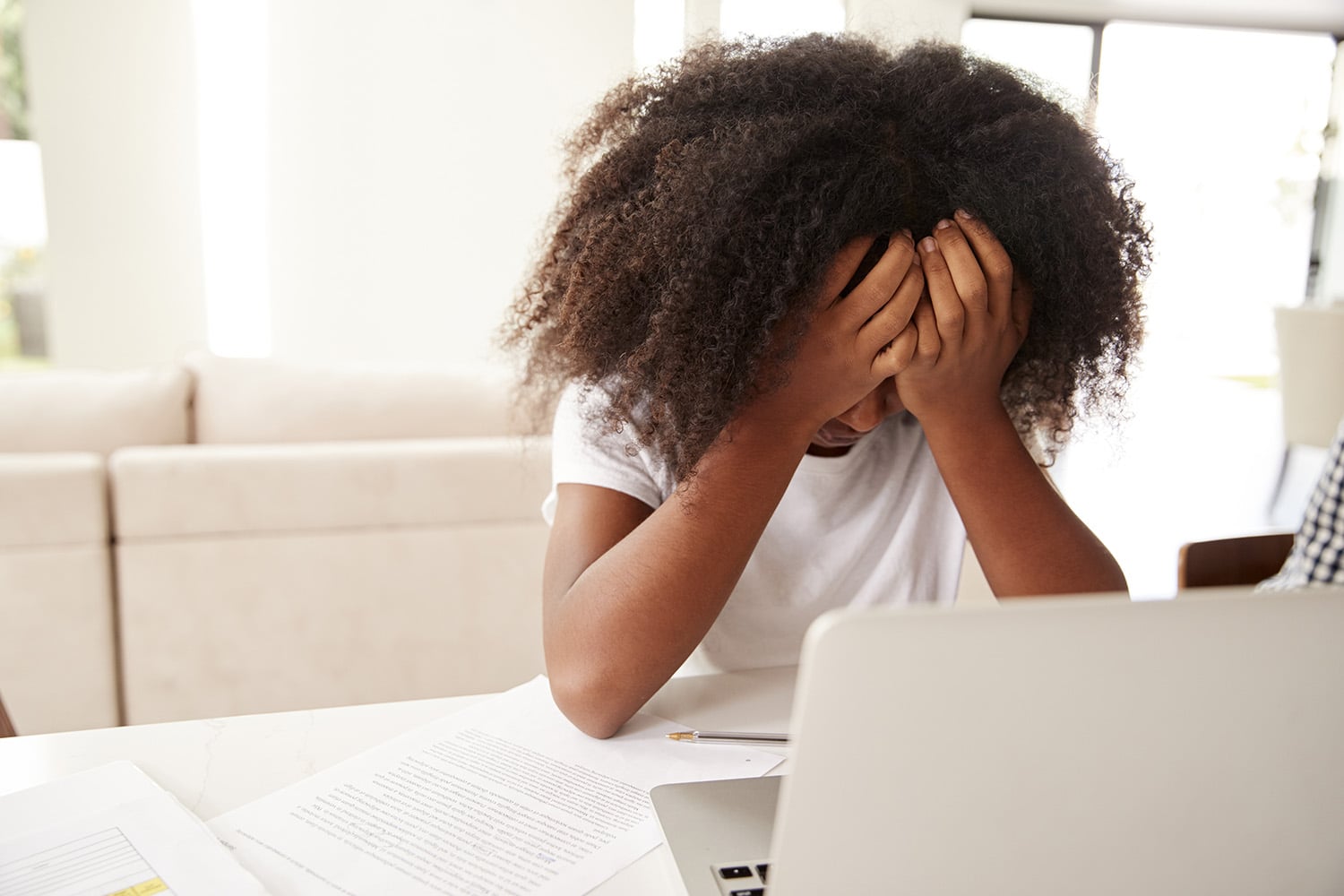 young girl with head in her hands in front of open computer