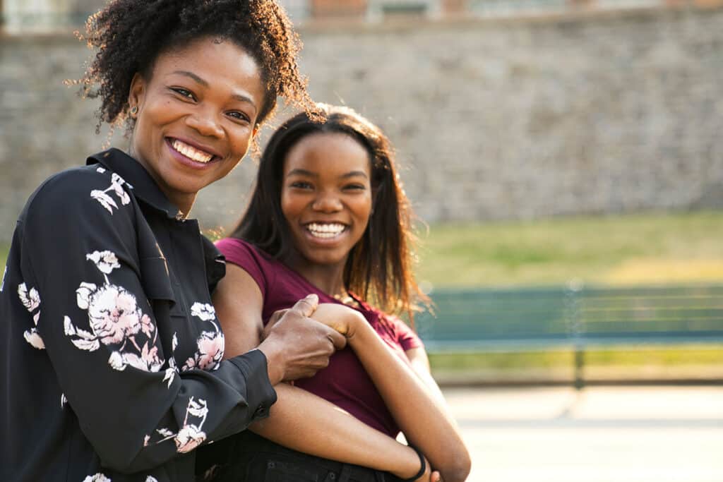 mother and daughter holding hands and smiling at camera