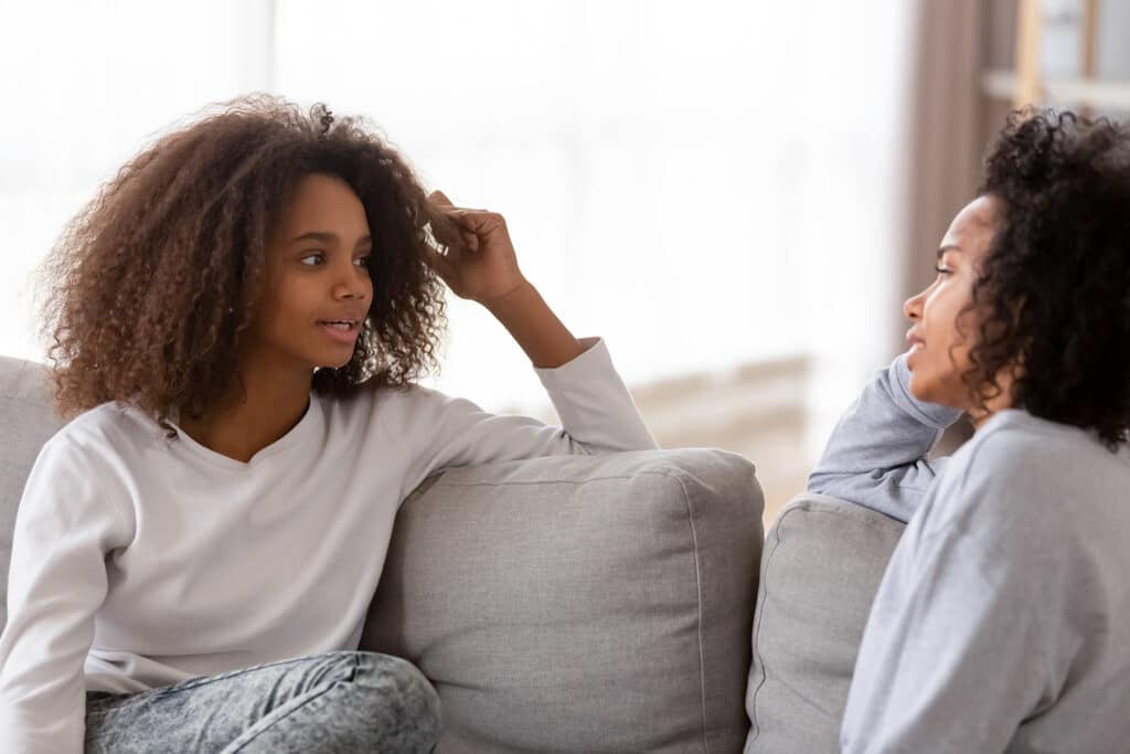 teen girl talking to her mom on a couch