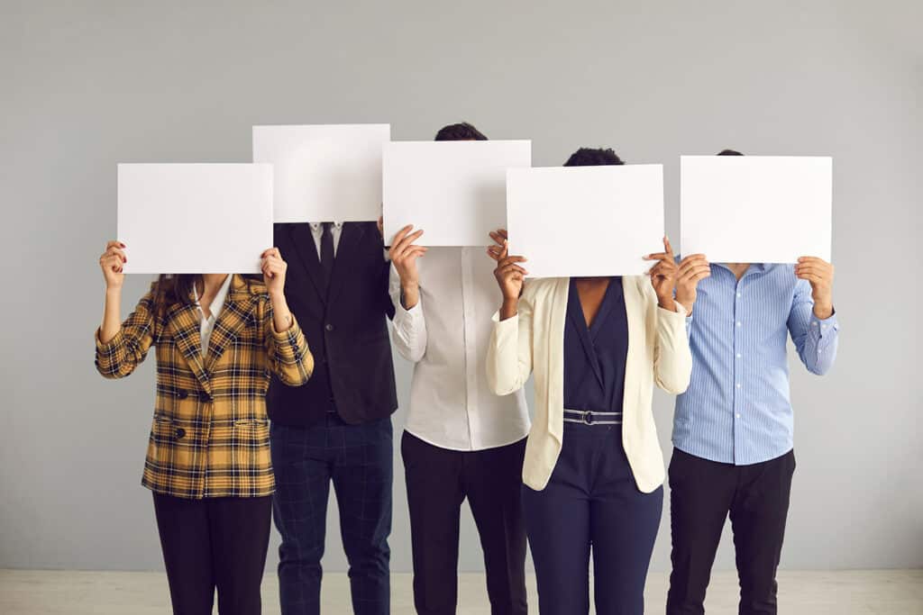 five people holding white cards over their face to make them anonymous