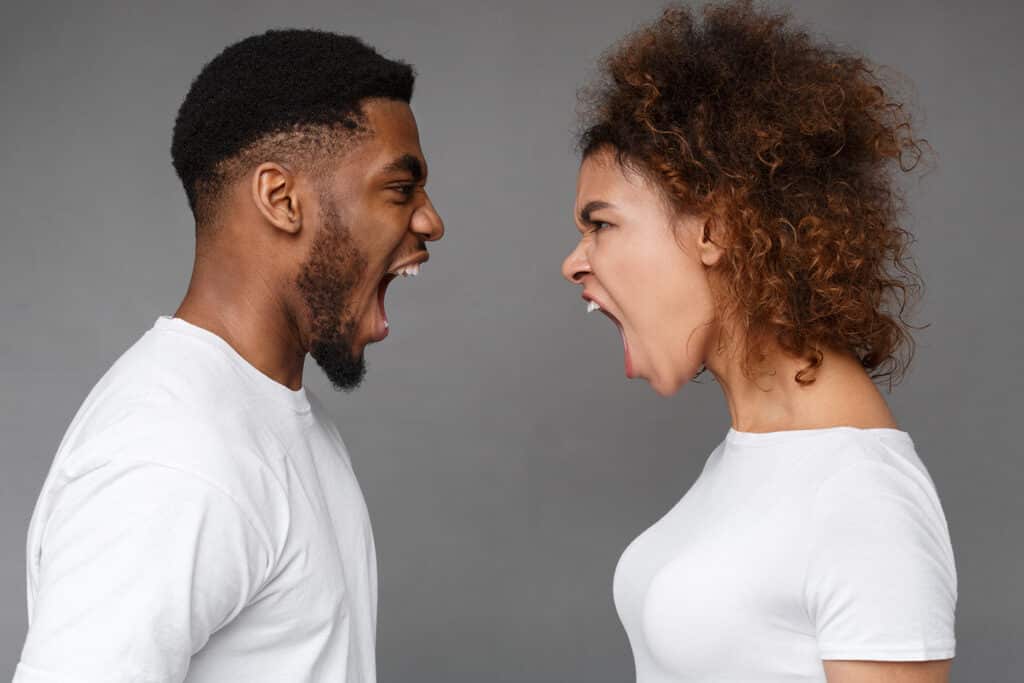 young couple wearing white shirts yelling in each other's faces