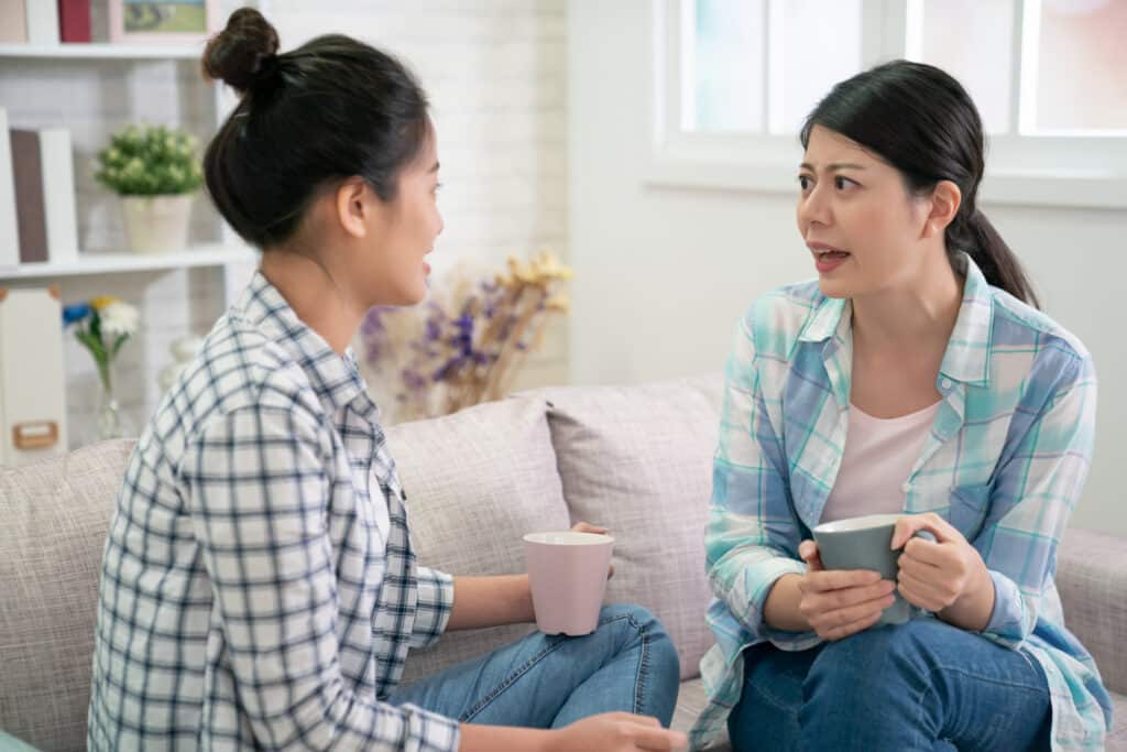 two women talk to each other over coffee