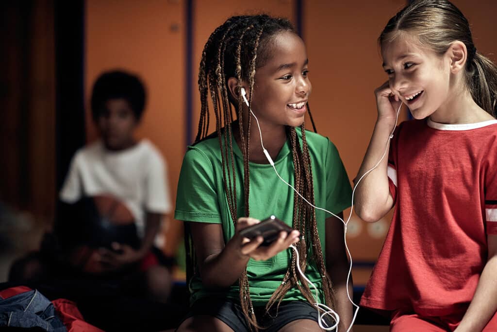 two young girls listening to music and smiling