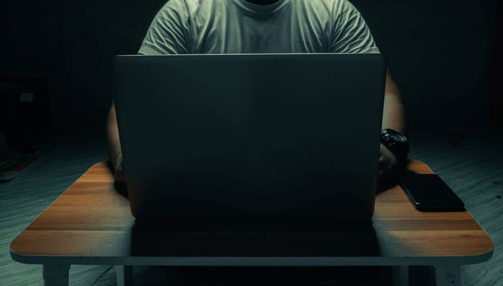 person in dark room on laptop