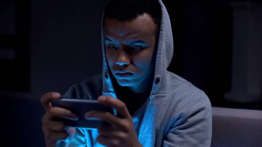 teen boy wearing hoodie looking at his phone