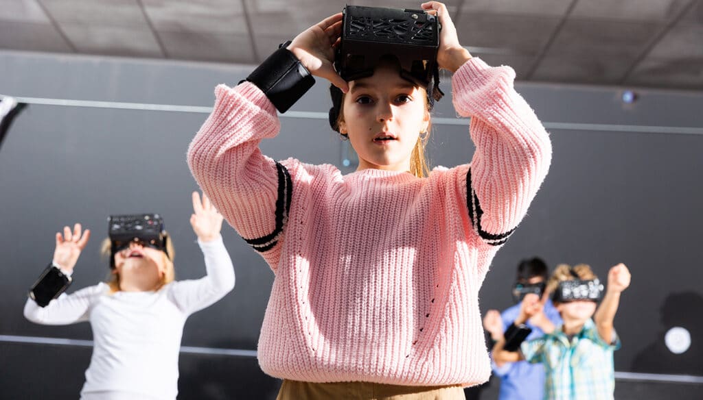 kids using virtual reality headsets with young girl taking hers off