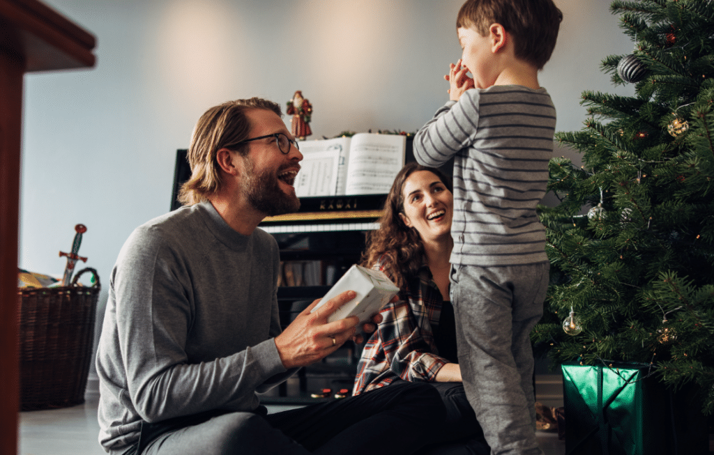 excited child receives Christmas presents from parents